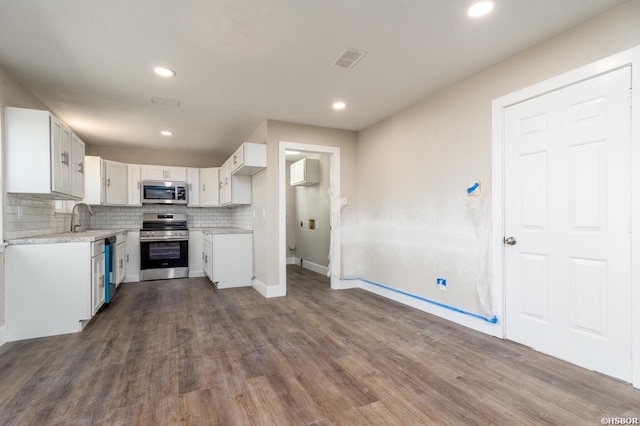 kitchen featuring stainless steel appliances, tasteful backsplash, light countertops, visible vents, and white cabinetry