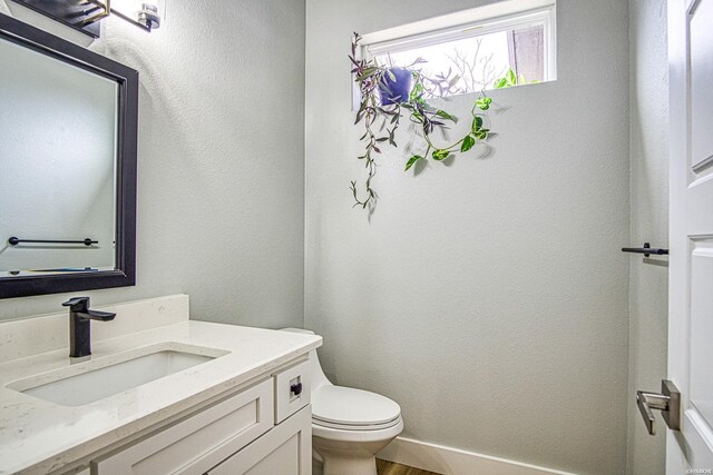 bathroom featuring baseboards, vanity, toilet, and wood finished floors