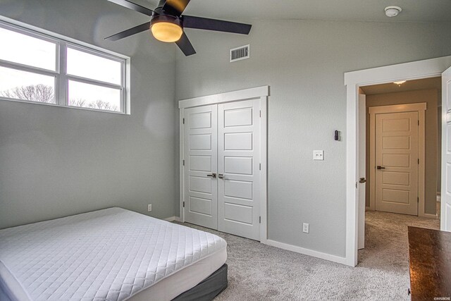 bedroom with light carpet, vaulted ceiling, a closet, and visible vents