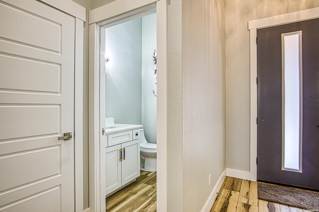 corridor featuring light wood-type flooring and baseboards