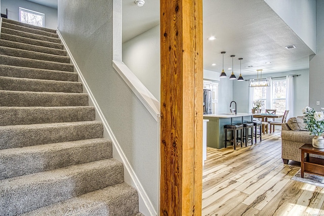 stairs featuring baseboards, wood finished floors, and a healthy amount of sunlight