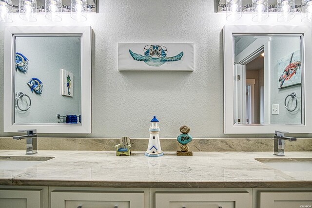 bathroom with a textured wall, a sink, and double vanity