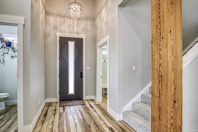 foyer entrance featuring baseboards, stairway, and wood finished floors