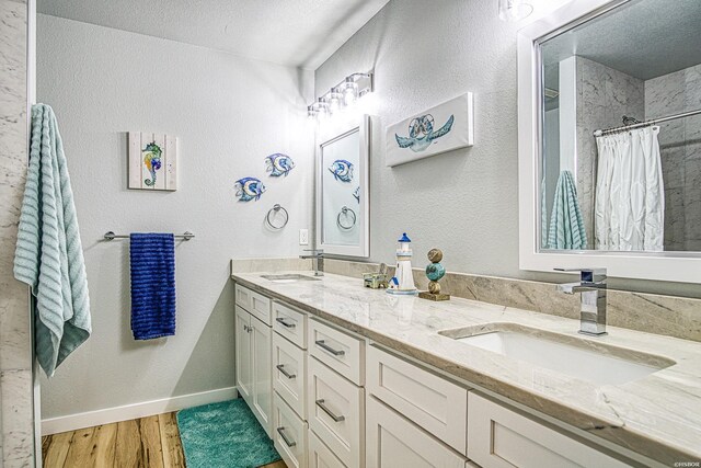 full bath with a shower with curtain, double vanity, a sink, and wood finished floors