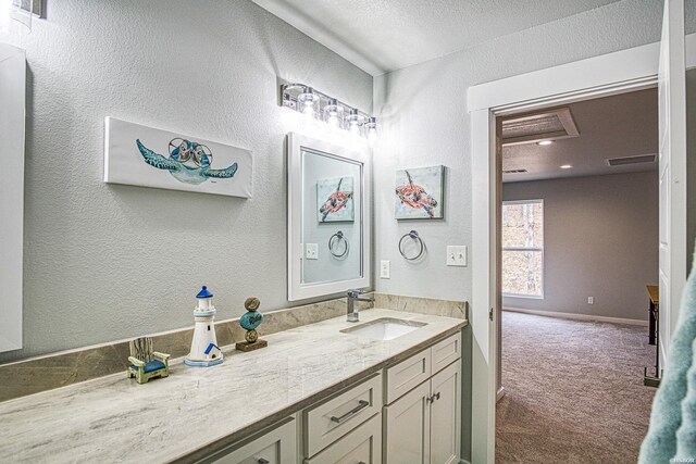 bathroom with a textured wall, visible vents, and vanity