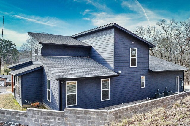 view of home's exterior featuring central AC and roof with shingles