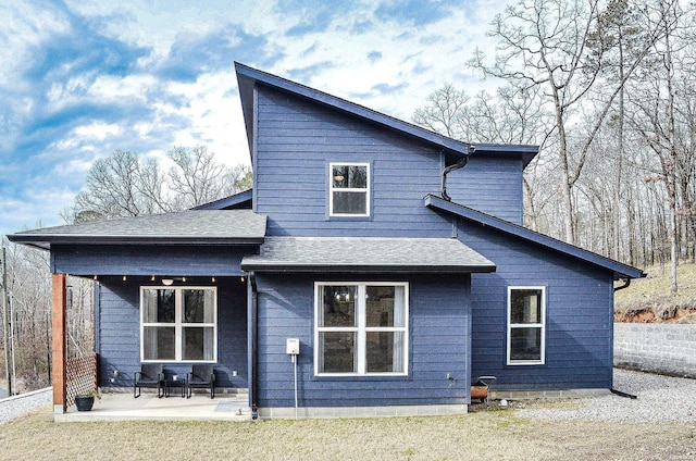 back of property featuring a patio area and roof with shingles