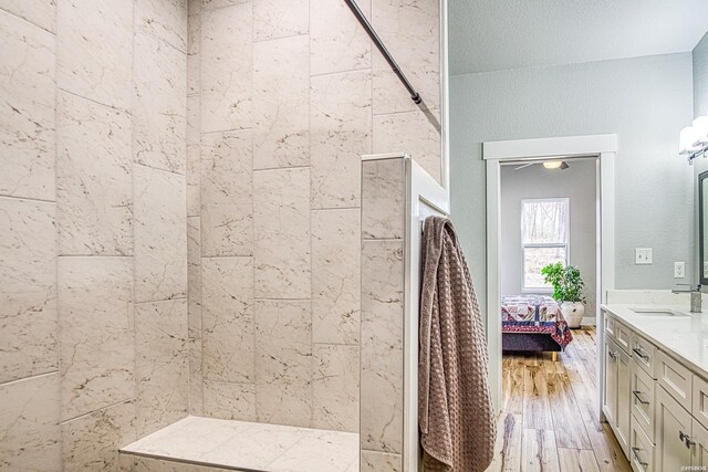 full bathroom with tiled shower, vanity, ensuite bath, and wood finished floors