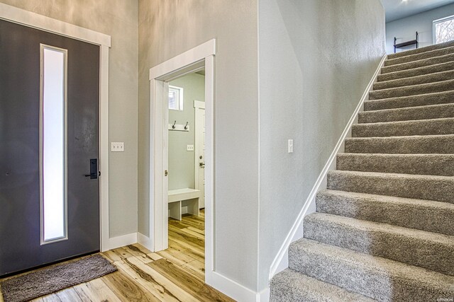 foyer with elevator, baseboards, stairway, and wood finished floors