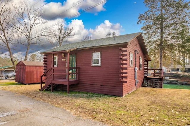 cabin featuring an outbuilding, a storage shed, a front lawn, and log siding