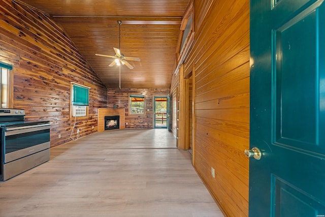 interior space with stainless steel electric range oven, light wood finished floors, wooden ceiling, wood walls, and a warm lit fireplace