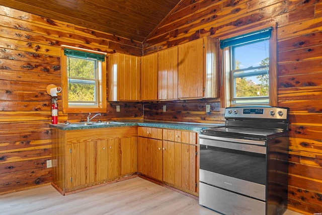 kitchen with dark countertops, lofted ceiling, brown cabinetry, a sink, and stainless steel range with electric stovetop