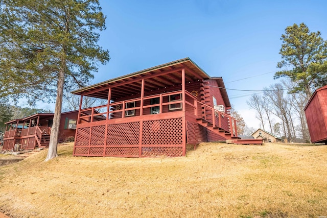 back of property featuring stairway, log siding, and a yard