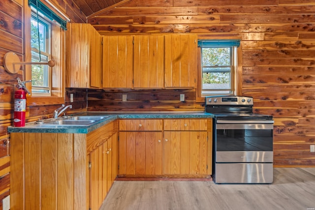 kitchen with electric stove, brown cabinetry, dark countertops, and a sink