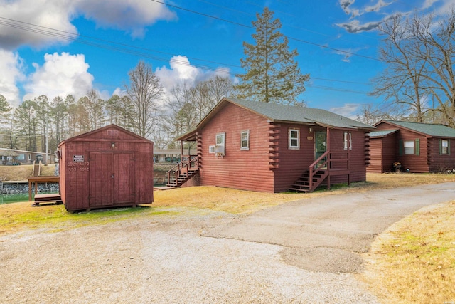 view of side of home with a storage unit, log siding, and an outdoor structure