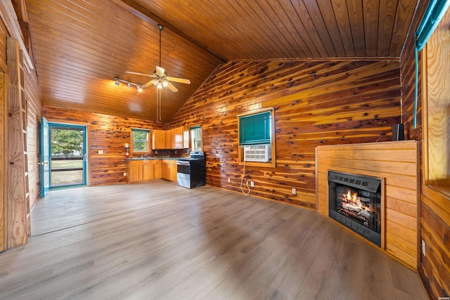 kitchen featuring light wood finished floors, lofted ceiling, wooden ceiling, stainless steel electric range oven, and a lit fireplace