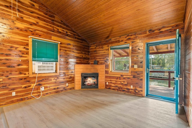 unfurnished living room featuring a warm lit fireplace, wooden walls, wood finished floors, vaulted ceiling, and cooling unit