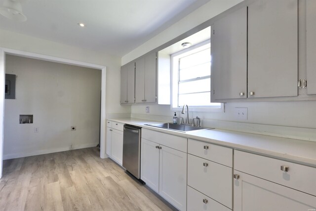 kitchen with a sink, light countertops, light wood-type flooring, electric panel, and dishwasher