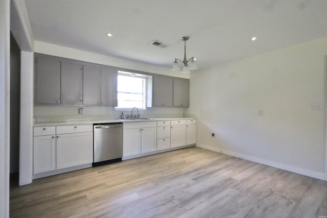 kitchen with light countertops, hanging light fixtures, visible vents, stainless steel dishwasher, and a sink