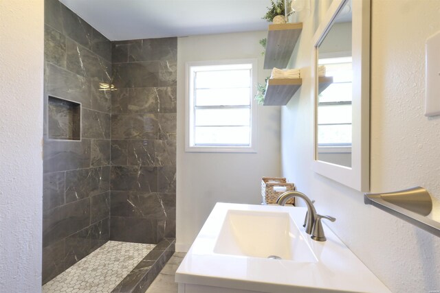 bathroom with tiled shower and vanity