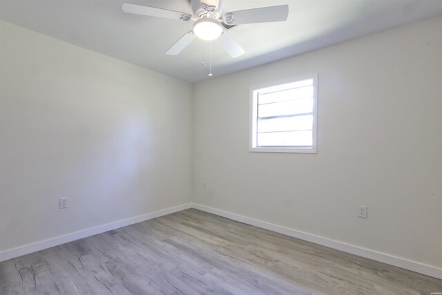 empty room featuring ceiling fan, light wood finished floors, and baseboards