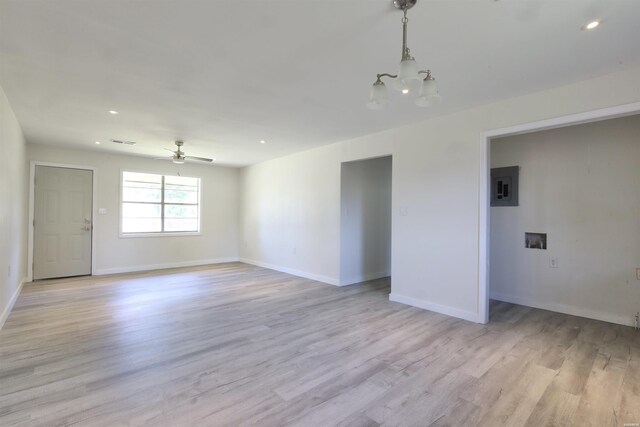 empty room with recessed lighting, ceiling fan with notable chandelier, baseboards, light wood-type flooring, and electric panel