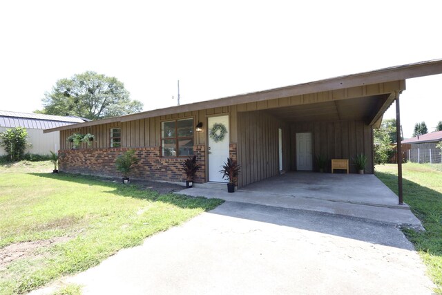 single story home with a carport, a front lawn, board and batten siding, and driveway