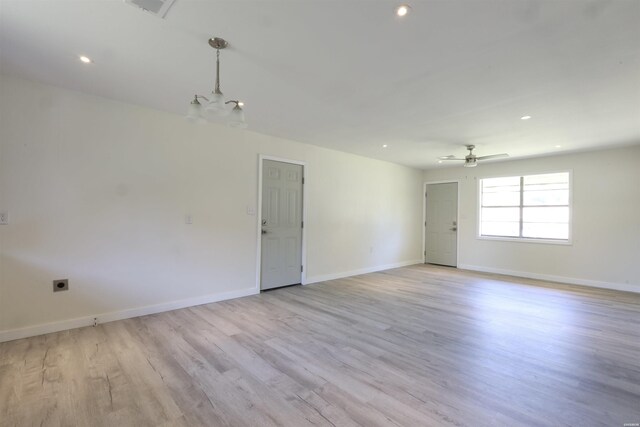 spare room with recessed lighting, light wood-style flooring, baseboards, and ceiling fan with notable chandelier