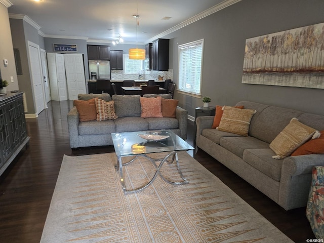 living room featuring dark wood-style flooring, crown molding, and baseboards