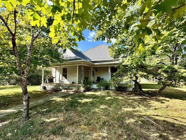 farmhouse-style home featuring covered porch, metal roof, and a front lawn