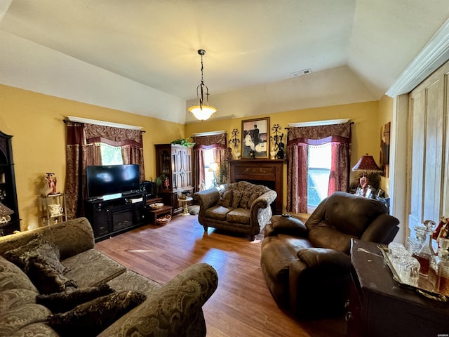 living area featuring visible vents, vaulted ceiling, and wood finished floors