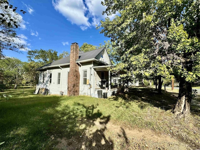 view of side of home with a yard and a chimney