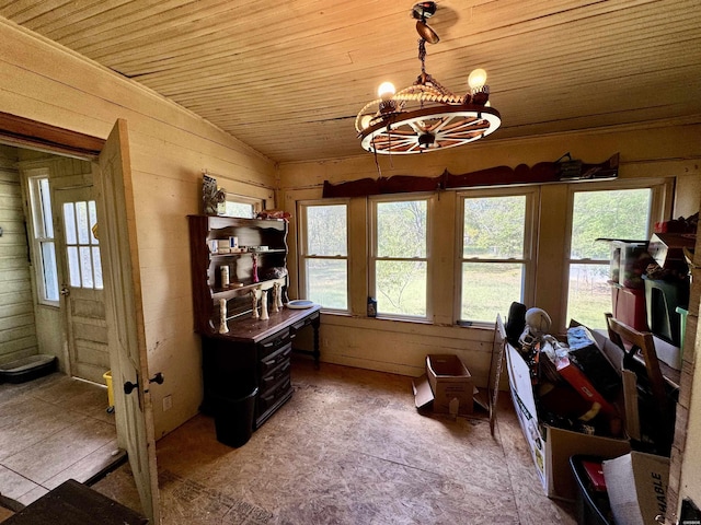 living area with lofted ceiling, wooden ceiling, a notable chandelier, and wooden walls