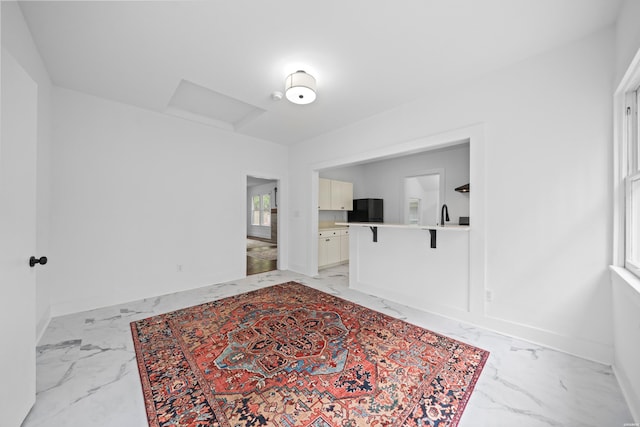 interior space featuring attic access, baseboards, and marble finish floor