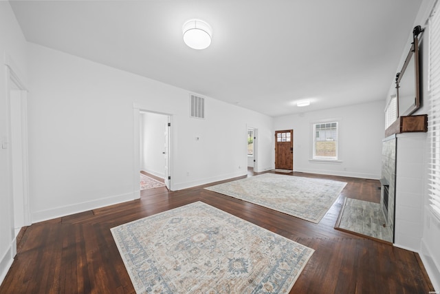 foyer entrance with visible vents, wood finished floors, a fireplace, baseboards, and a barn door