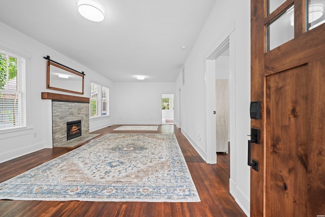 interior space with baseboards, plenty of natural light, a fireplace, and dark wood-style flooring