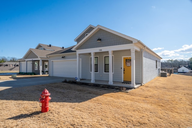 view of front of property with driveway, covered porch, a garage, and central AC