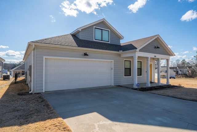 view of front of home with roof with shingles, a porch, central AC unit, a garage, and driveway