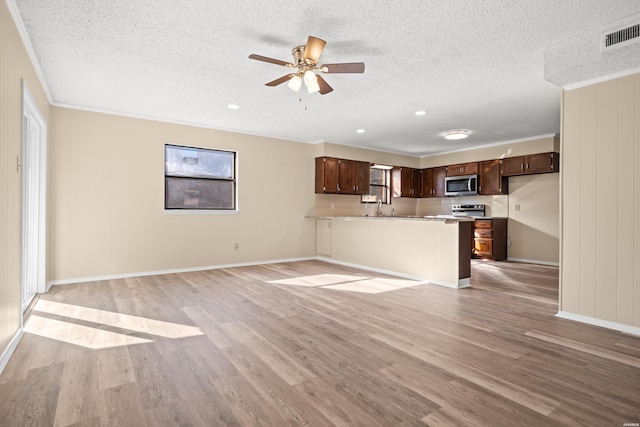 unfurnished living room with baseboards, visible vents, a textured ceiling, and light wood finished floors