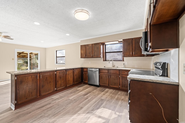 kitchen featuring stainless steel appliances, light wood-style floors, plenty of natural light, and a peninsula