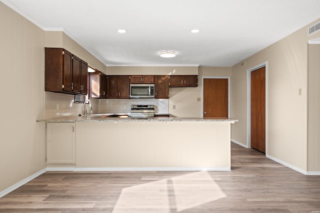 kitchen with a peninsula, dark brown cabinetry, stainless steel appliances, and light wood finished floors