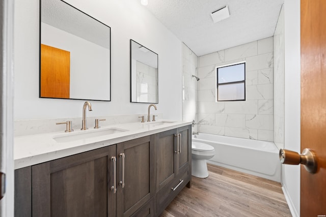 full bath with a textured ceiling, tub / shower combination, a sink, and wood finished floors