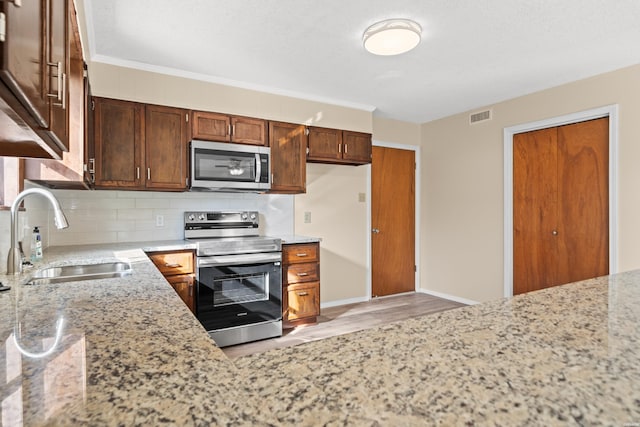 kitchen with tasteful backsplash, visible vents, appliances with stainless steel finishes, light stone counters, and a sink