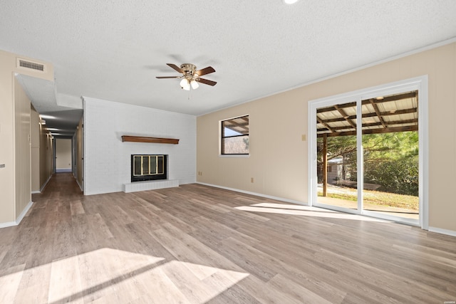 unfurnished living room featuring light wood-type flooring, a fireplace, visible vents, and a healthy amount of sunlight