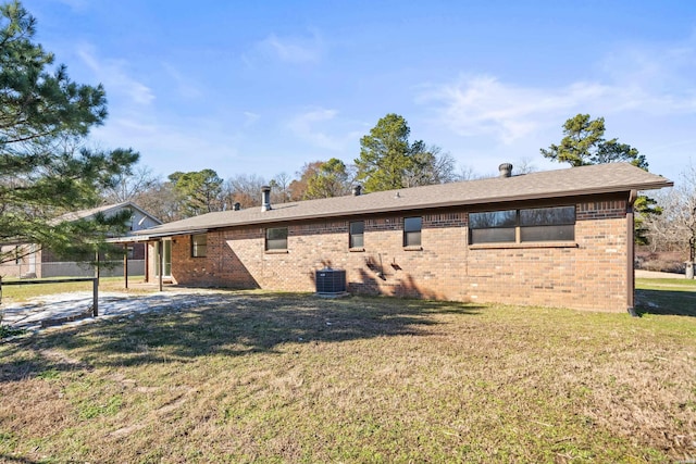 back of property featuring brick siding, cooling unit, and a yard