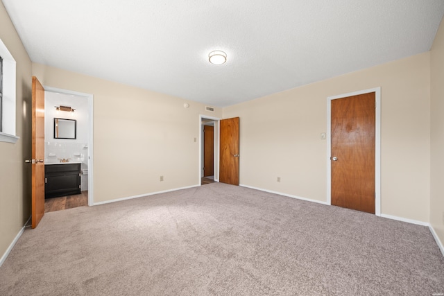 unfurnished bedroom with ensuite bathroom, carpet, and baseboards