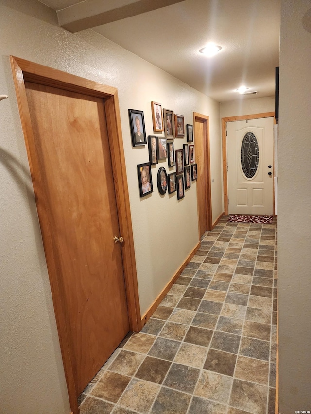 hallway featuring stone finish floor and baseboards