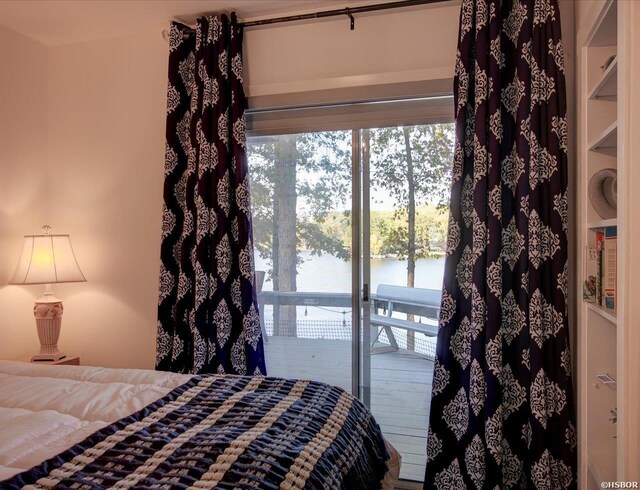 bedroom featuring a water view and access to exterior