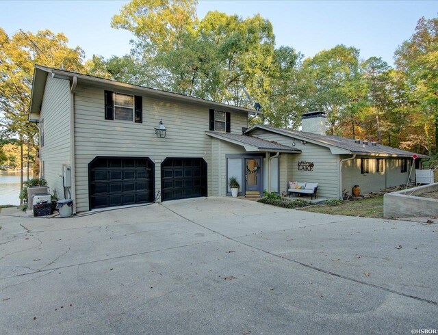 view of front facade featuring a garage, driveway, and a chimney