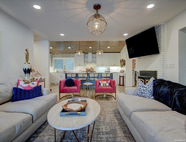 living room with vaulted ceiling, a brick fireplace, wood finished floors, and recessed lighting